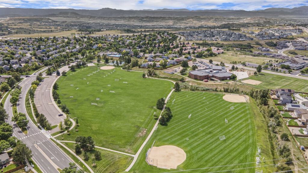 High-quality aerial drone image of a park with baseball fields and views of the surrounding area.