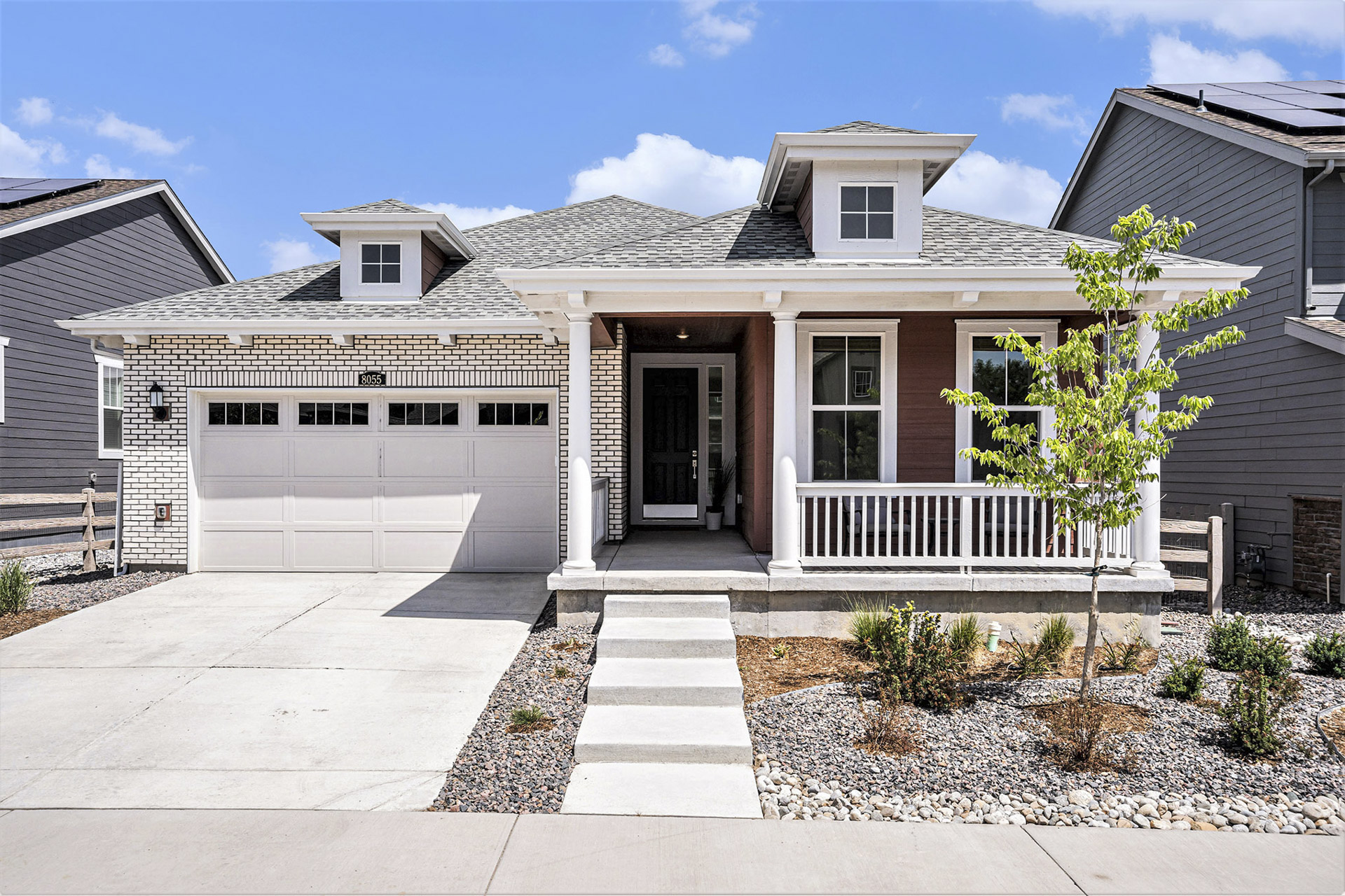 Front exterior of a newly built ranch-style home with a two-car garage and a welcoming porch.