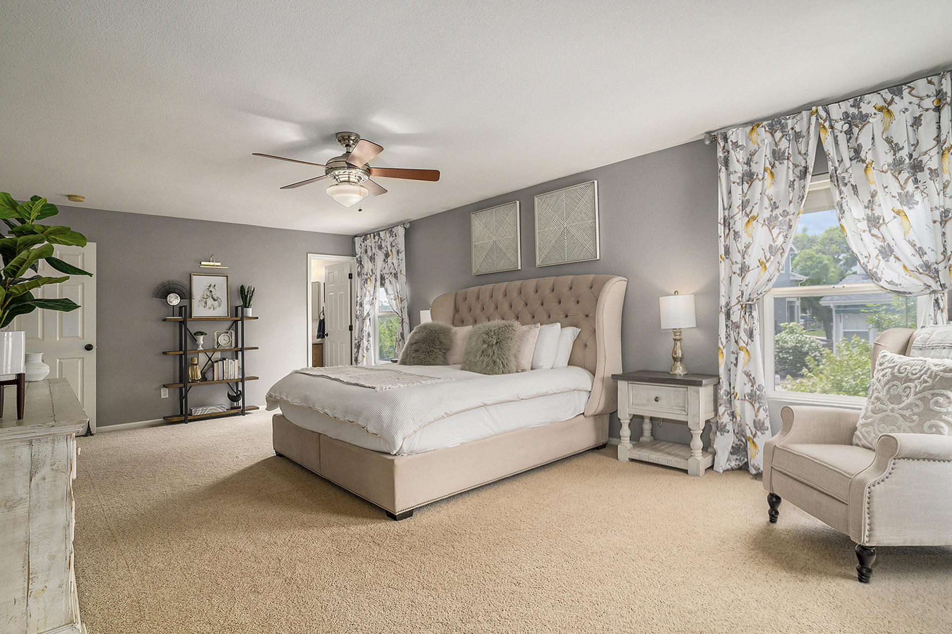 Spacious primary bedroom with natural light, a walk-in closet, primary bathroom, carpeted flooring, and a ceiling fan.