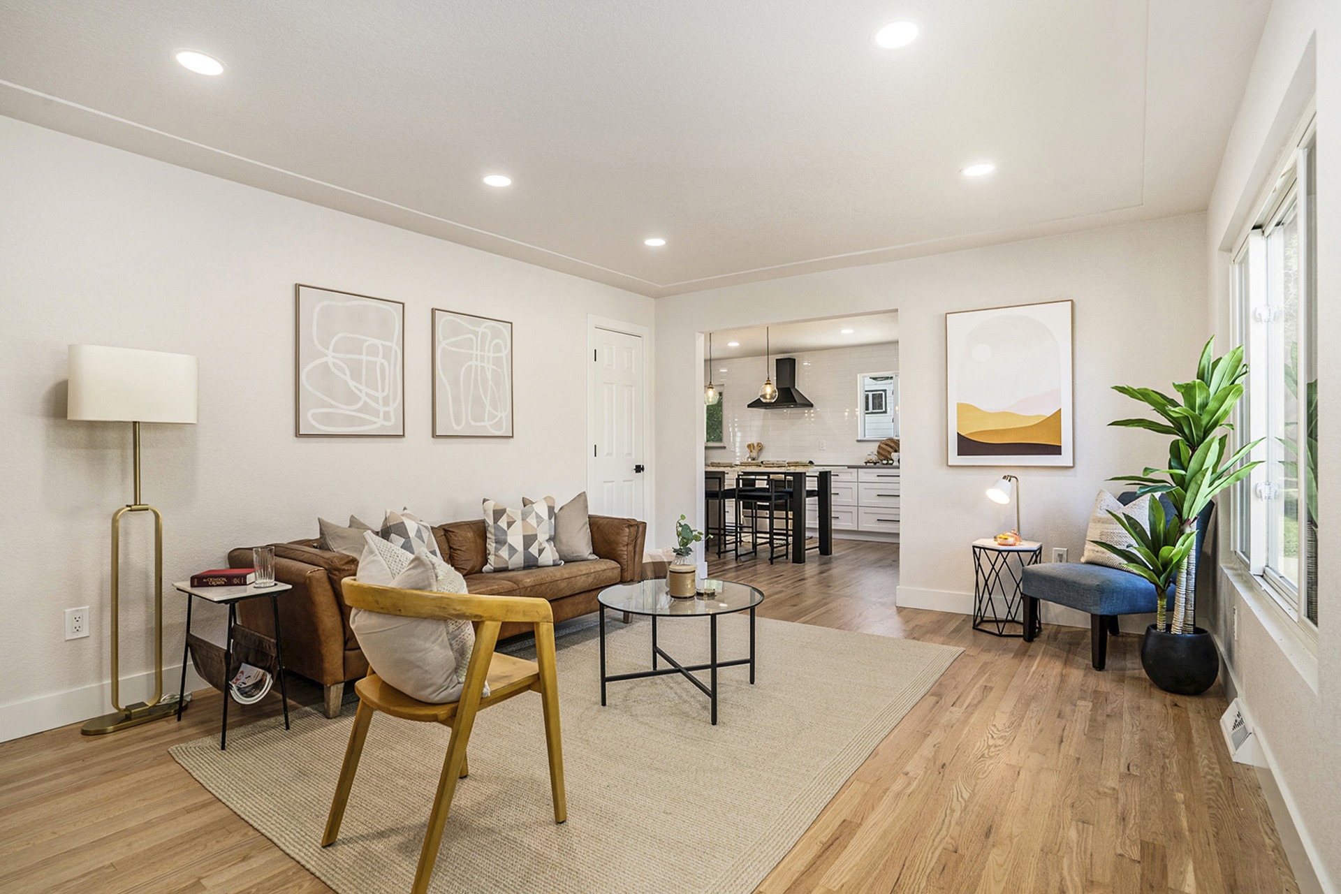 Bright, updated living room with modern lighting, wood floors, and a large picture window.